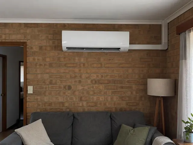 Wall-mounted split system indoors on a brick feature wall above a sofa in a living room in Davoren Park
